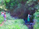 Fijian woman washing clothes in the stream with her children